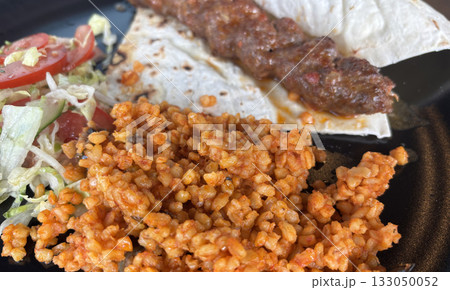 Turkish chicken kebab with bulgur, salad and lavash close up 133050052