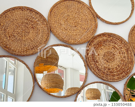 Round woven mirrors on bright cafe wall. Natural textures, geometry, and warm handcrafted interior style. 133050488