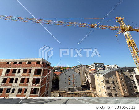 Unfinished red brick apartment building under clear sky. Urban development, construction progress, and city growth. Unfinished red brick apartment building under clear sky. Urban development, construction progress, and city growth. 133050513