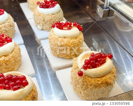 Raspberry and red currant cream tartlets in pastry shop. Elegant dessert styling, harmony of fruit color, and patisserie aesthetics. Raspberry and red currant cream tartlets in pastry shop. Elegant dessert styling, harmony of fruit color, and patisserie aesthetics. 133050598