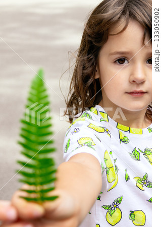 Toddler girl with a green fern leaf in the summer park. Toddler girl with a green fern leaf in the summer park. 133050902