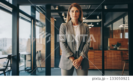A business woman in a smart outfit stands in a modern office with large windows. She looks ready for a meeting, showcasing professionalism and confidence in a stylish workspace. A business woman in a smart outfit stands in a modern office with large windows. She looks ready for a meeting, showcasing professionalism and confidence in a stylish workspace. 133050921