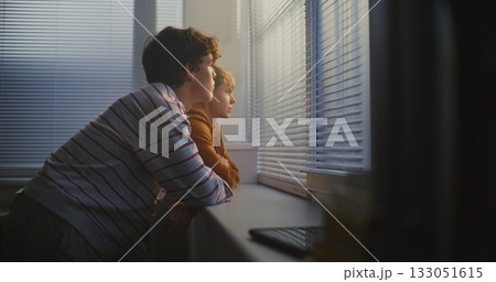 Two Teenage Boys Stand by Classroom Large Window, Quietly Talking and Watching World Outside 133051615