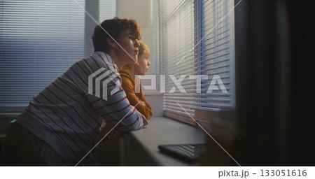 Two Teenage Boys Stand by Classroom Large Window, Quietly Talking and Watching World Outside 133051616
