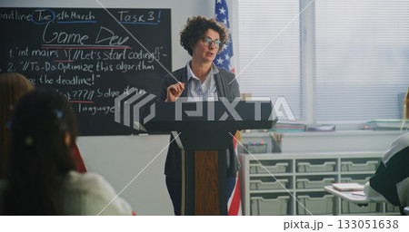Female American Teacher Stands at Podium, Guiding Lesson With Humor and Warmth 133051638