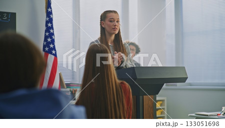 American Teenage Girl Delivers Expressive Speech, Gesturing Confidently With US Flag American Teenage Girl Delivers Expressive Speech, Gesturing Confidently With US Flag 133051698