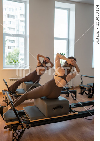 Balancing side plank during Pilates, Female Pilates trainer performs controlled side plank 133053174