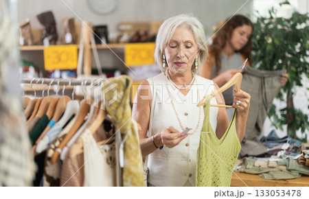 Woman chooses set of clothes for the summer. Visitor to the boutique examines new summer collection of clothes 133053478