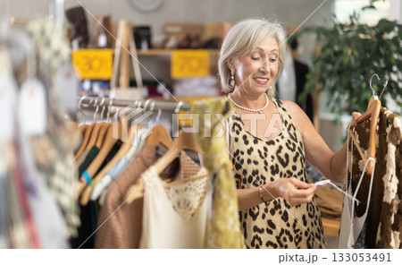 Elderly woman choosing summer clothes in store Elderly woman choosing summer clothes in store 133053491