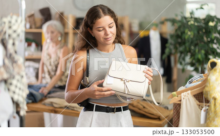 Smiling woman choosing a fashionable handbag in boutique 133053500