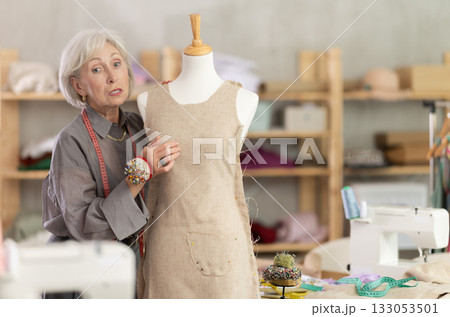 Woman seamstress adjusts clothes on mannequin 133053501