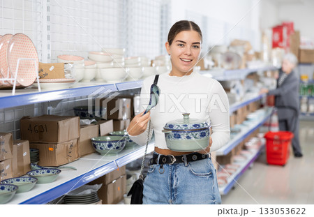 Young female shopper choosing porcelain soup tureen at Asian store 133053622