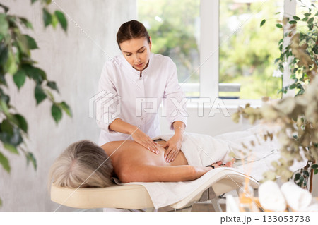 Young woman doing back massage to elderly woman Young woman doing back massage to elderly woman 133053738