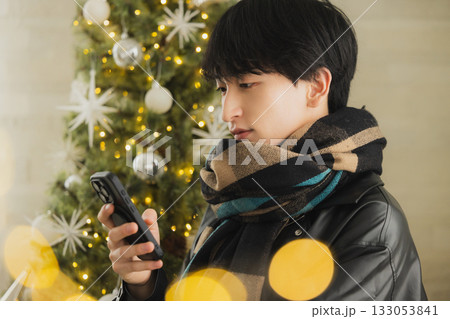 クリスマスツリーの前でプレゼントを持つ男性 クリスマスツリーの前でプレゼントを持つ男性 133053841