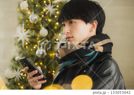 クリスマスツリーの前でプレゼントを持つ男性 133053842