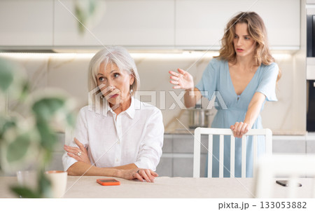 Quarrel of an mature mother and adult daughter at home. Adult daughter is unhappy with elderly mother Quarrel of an mature mother and adult daughter at home. Adult daughter is unhappy with elderly mother 133053882