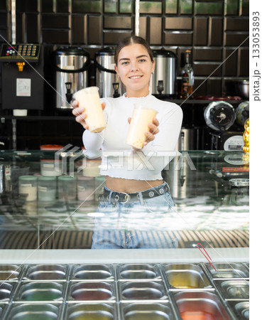 Friendly young saleswoman inviting to try aromatic bubble tea 133053893