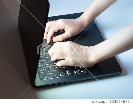 暗闇でノートパソコンのキーボードを打つ指 133054675