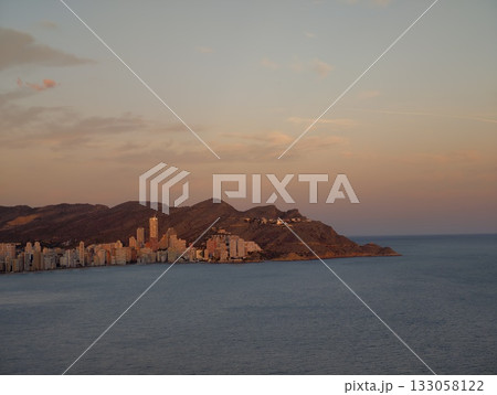 gentle twilight over tranquil seaside cityscape, calm dusk glow illuminating distant city 133058122