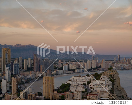 elegant seaside city during sunset hour, vibrant coastal metropolis illuminated by evening golden 133058124