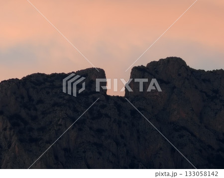 vivid dusk over rugged peaks, colorful twilight illuminating spiky summits against evening sky 133058142