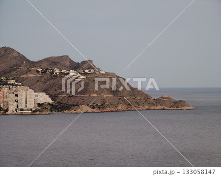 sunlit hillside with pastel homes, quiet harbor community with rustic buildings and serene waters 133058147