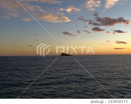 idyllic island sunset casting soft pastel colors over restful coastal scene with shimmering 133058173