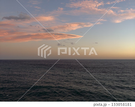 distant island illuminated by sunset, vast evening sky with distant island and gentle water glow 133058181