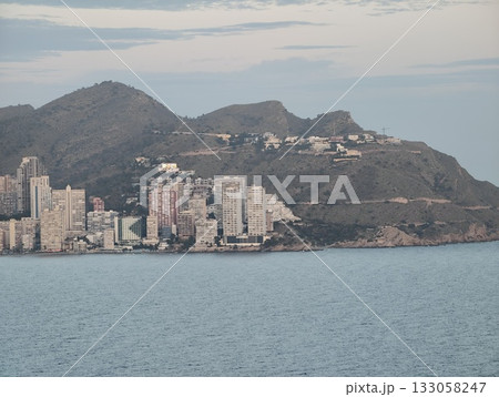sunlit urban highrise group positioned beside peaceful water body with detailed facade focus 133058247