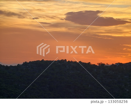 evening sunset view, calm twilight scene featuring illuminated clouds above gentle hill silhouettes evening sunset view, calm twilight scene featuring illuminated clouds above gentle hill silhouettes 133058256