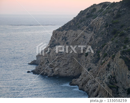 sunset bathes rugged rocks in gentle light, bold seaside landscape with dramatic cliffs and lively 133058259