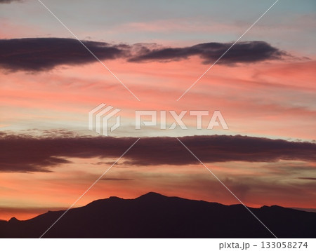 dusk mountain scene, cinematic sunset casts colorful hues over mountain silhouette and landscape 133058274