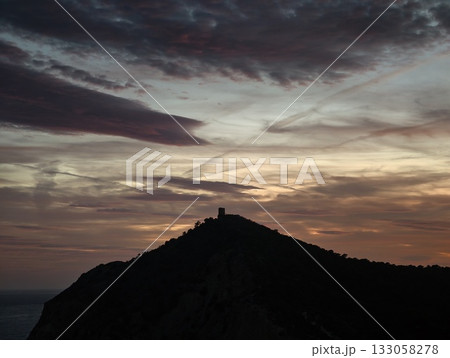stormy fortress silhouette, silhouette of castle beneath stormy skies indicating tension and drama 133058278