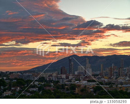 vibrant sunset over metropolitan area with towering glass buildings and scenic mountain backdrop 133058293