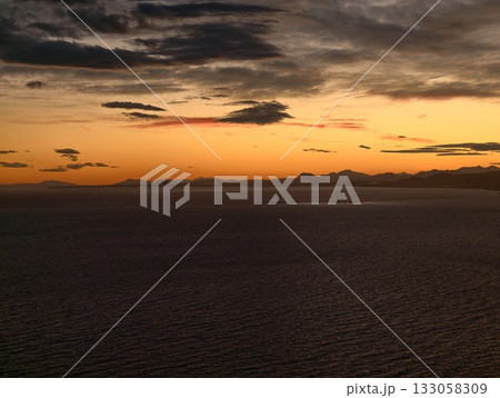 calm maritime scene at dusk, serene horizon bathed in amber light reflecting on gentle waves 133058309