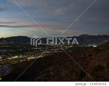 captivating hillside vantage point showcasing sparkling urban lights and remote mountain outlines 133058318