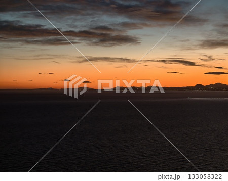 vivid sunset scene, vibrant sunset casting warm tones across ocean with prominent cloud formations vivid sunset scene, vibrant sunset casting warm tones across ocean with prominent cloud formations 133058322