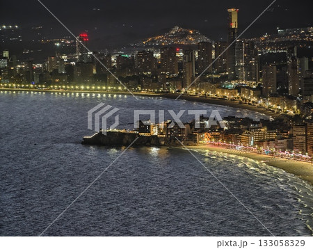 nighttime waterfront with busy street, illuminated shoreline with active harbor and rocky cliffs nighttime waterfront with busy street, illuminated shoreline with active harbor and rocky cliffs 133058329