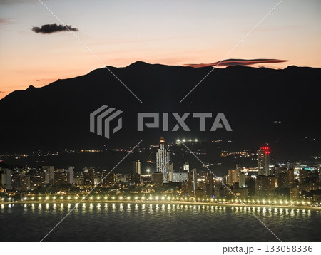 serene water under bright city lights, nighttime seaside scene with vibrant city skyline reflections 133058336