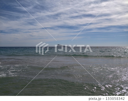 bright ocean with sandy beaches, sunlit coastline featuring gentle surf and tropical summery 133058342