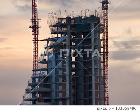 urban construction scene, city skyline behind partially built tower with construction equipment urban construction scene, city skyline behind partially built tower with construction equipment 133058490