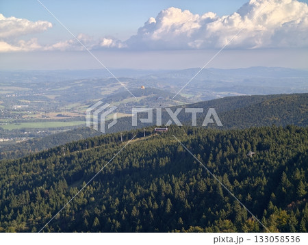 scenic views with peaceful atmosphere, tranquil ridge capped by vibrant clouds over forested expanse 133058536