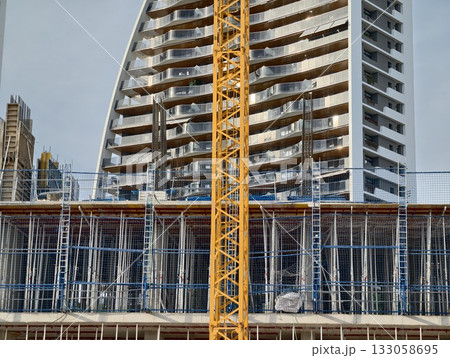 giant yellow crane towering over site, massive yellow crane positioned above structural elements 133058695