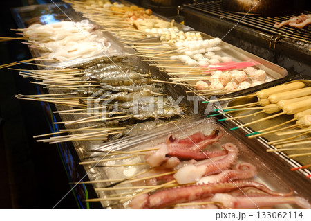 Grilled seafood and skewers at a bustling night market in an Asian city during the evening hours Grilled seafood and skewers at a bustling night market in an Asian city during the evening hours 133062114