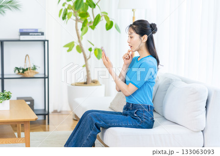 部屋でスマホを操作する女性 133063093