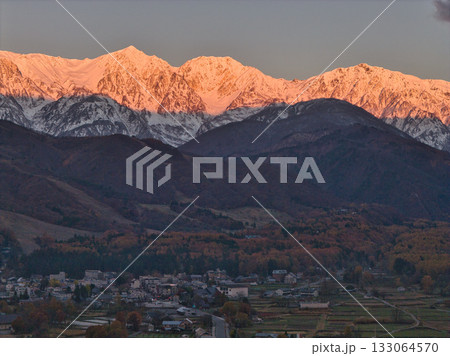 紅葉に染まる里山と冠雪した白馬三山のモルゲンロート　長野県白馬村（ドローンによる空撮） 133064570