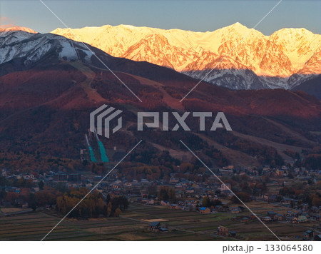紅葉に染まる八方尾根スキー場と冠雪した白馬連峰のモルゲンロート　長野県白馬村（ドローンによる空撮） 133064580