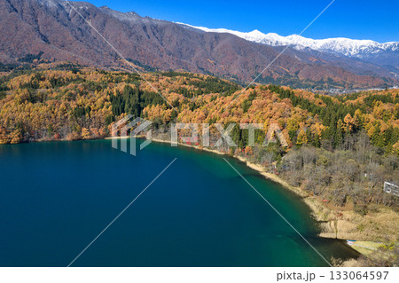 紅葉に包まれた青木湖と冠雪した白馬三山　長野県大町市（ドローンによる空撮） 133064597