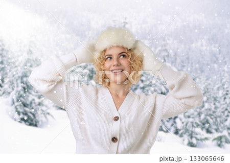 Woman smiles while wearing a warm hat in snowy winter landscape Woman smiles while wearing a warm hat in snowy winter landscape 133065646
