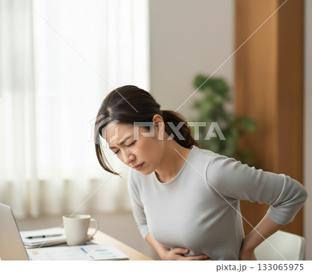 デスクワーク中に腹痛を感じる若い女性 133065975